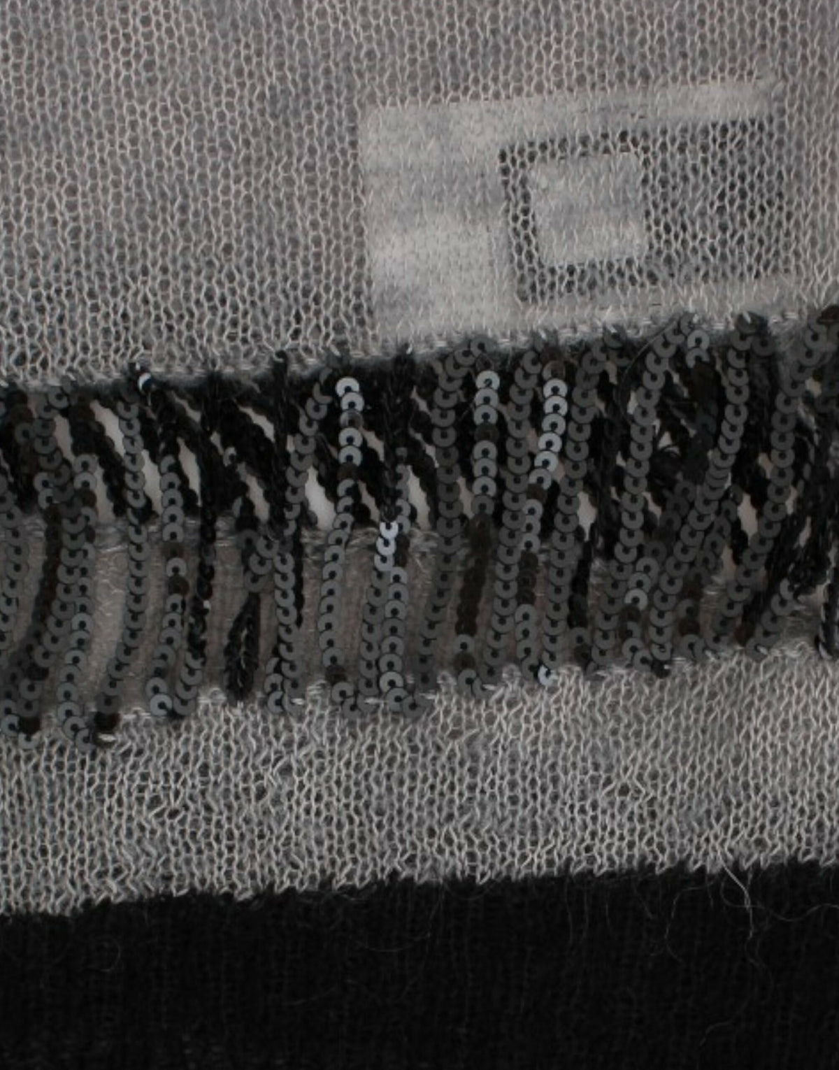 Costume National, pull asymétrique gris avec ornements.