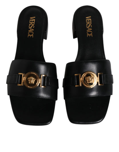 Sandales plates à enfiler en cuir noir avec plaque logo Versace.