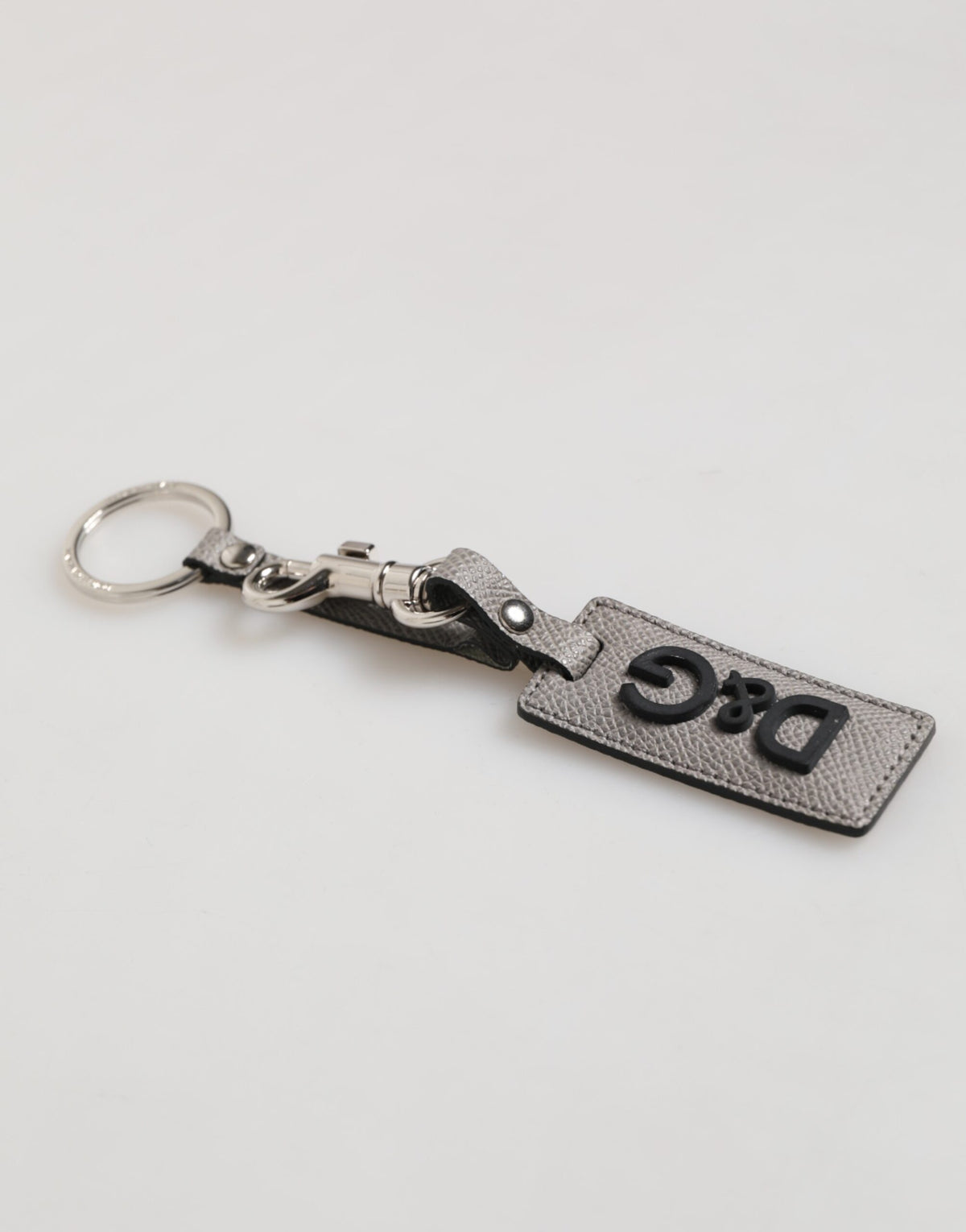 Porte-clés homme Dolce &amp; Gabbana en cuir gris avec anneau métallique et logo.