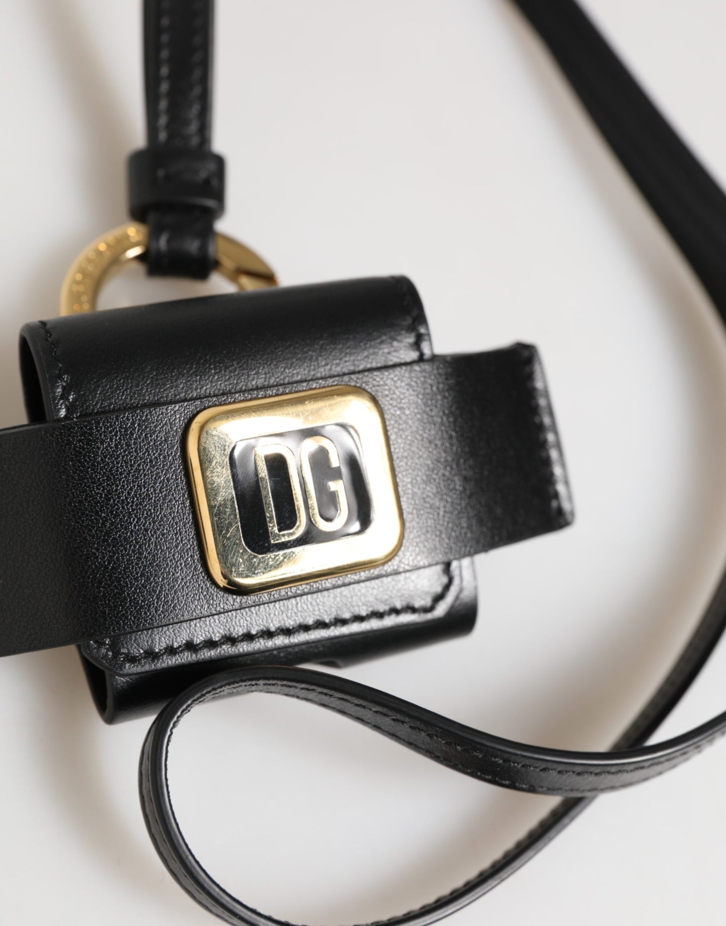 Étui Airpods Dolce & Gabbana en cuir noir avec plaque dorée en métal portant le logo DG.