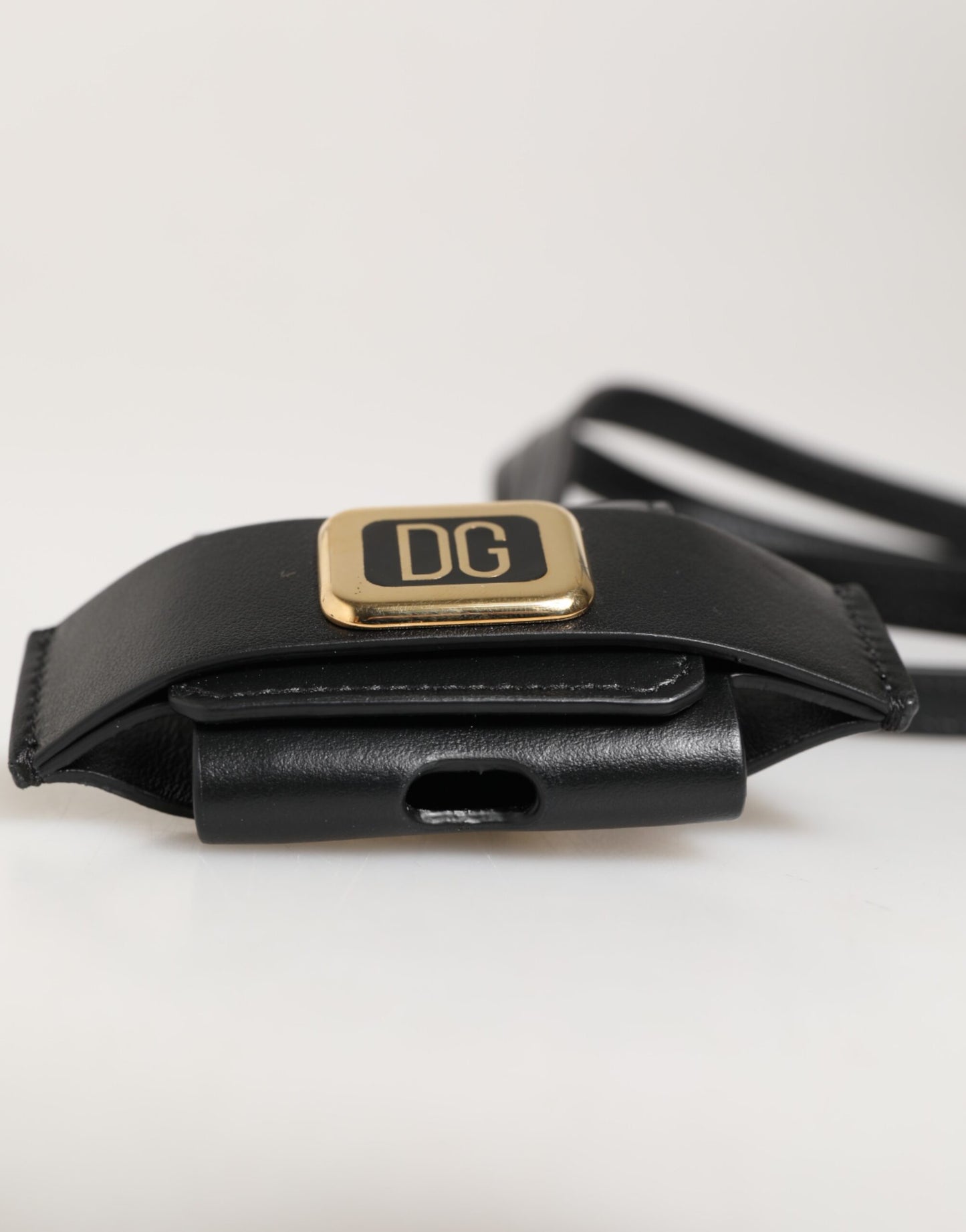 Étui Airpods Dolce & Gabbana en cuir noir avec plaque dorée en métal portant le logo DG.